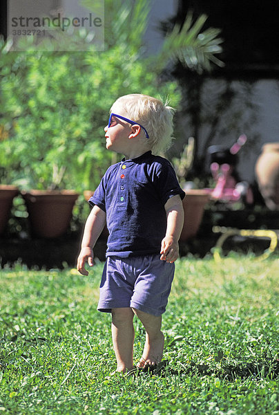 Zweijähriger mit Sonnenbrille im Garten