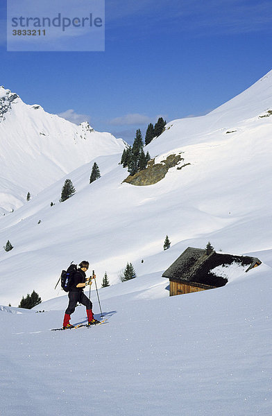 Schneeschuhgeherin an einer Hütte im Kleinwalsertal Österreich