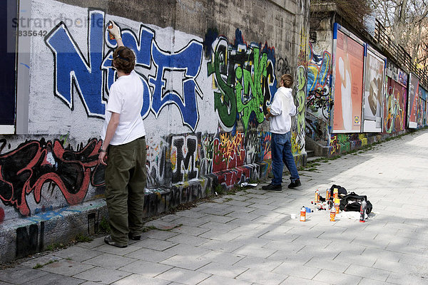 Graffity-Sprayer mit Atemschutz bei der Arbeit in Münchener Bahnunterführung
