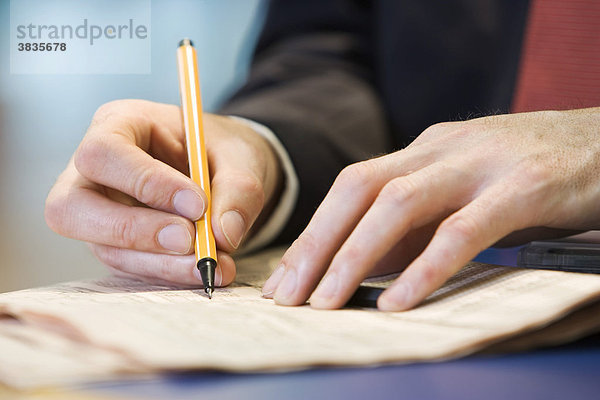 Hände eines Geschäftsmannes mit Stift in der rechten Hand am schreiben