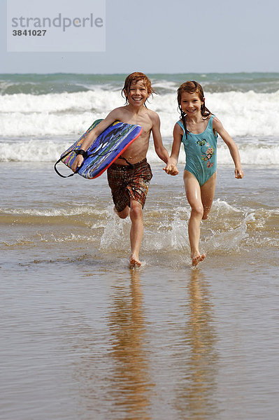Kinder mit Boogyboard und Wellen am Strand  Meer