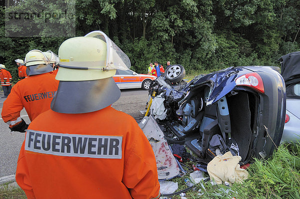 Ein Feuerwehrmann vor dem Wrack des Kleinwagens Renault Clio  in dem auf der B 39 drei Menschen ums Leben kamen  Kirchardt  Baden-Württemberg  Deutschland  Europa
