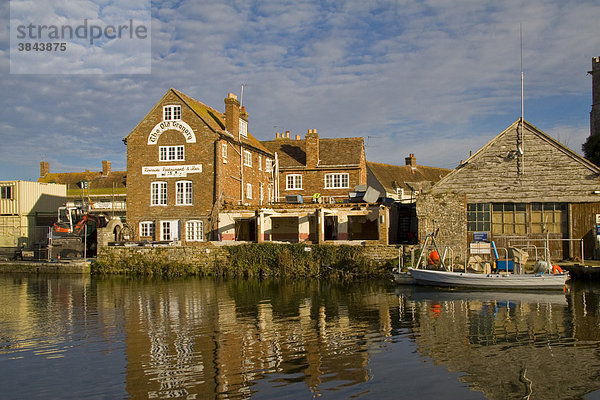 Fluss mit alten renovierten Gebäuden und Bootshaus mit Boot der Umweltbehörde am Kai  Wareham  Dorset  England  Großbritannien  Europa