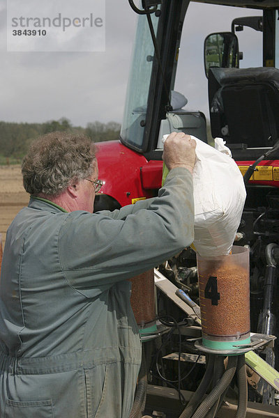 Farmer beim Nachfüllen einer Sämaschine mit beschichtetem Saatgut für Spinat  Dorset  England  Großbritannien  Europa