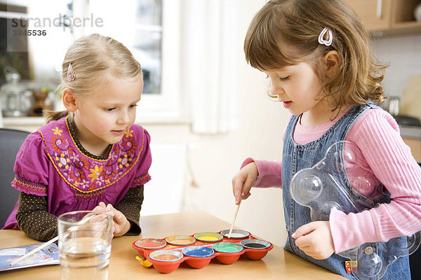 Zwei Mädchen malen mit Wasserfarben