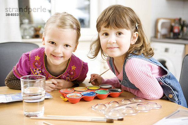 Zwei Mädchen malen mit Wasserfarben