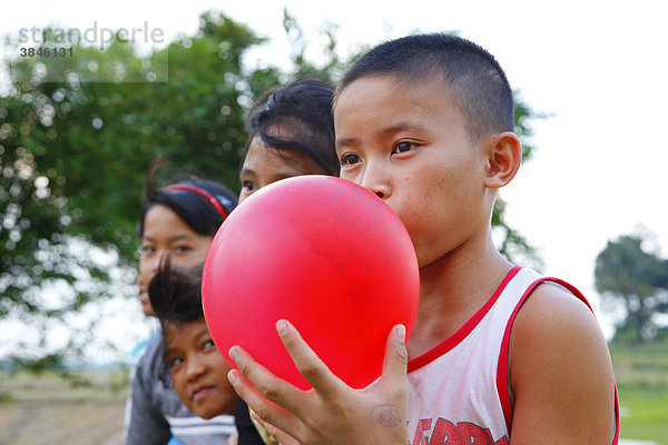 Junge bläst einen roten Luftballon auf  Kinderheim Margaritha  Marihat  Batak Region  Sumatra  Indonesien  Asien