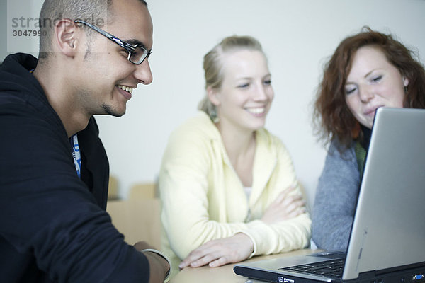 Drei junge Erwachsene besprechen sich am Laptop  Arbeitswelt