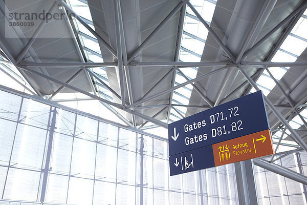 Hinweisschild auf Flughafen mit moderner Glasfassade