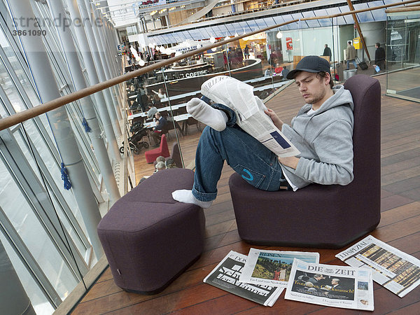 Junger Mann liest die deutsche Wochenzeitung Die Zeit auf dem Flughafen Arlanda in Stockholm  Schweden  Europa