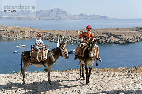 Zwei Kinder reiten auf Eseln  nahe Lindos  Insel Rhodos  Dodekanes  Griechenland  Europa