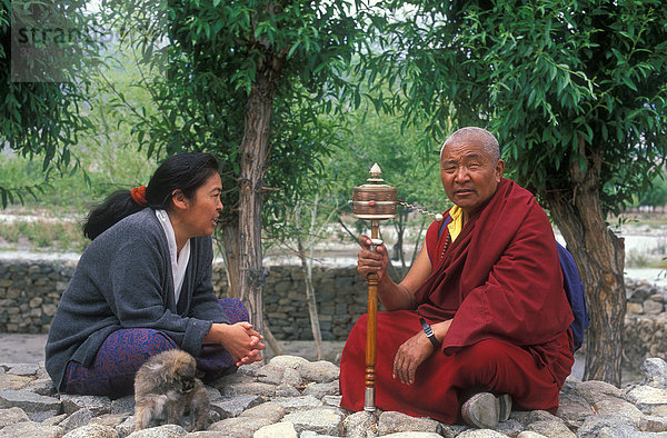 Buddhistischer Mönch mit Gebetsmühle  im Gespräch mit einer Frau  Ladakh  Himalaya  Nordindien  Indien  Asien