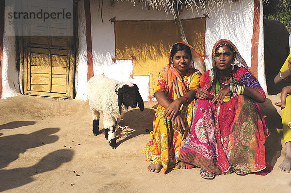 Frauen in bunten Saris vor traditionell bemaltem Wohnhaus  Wüste Thar  Rajasthan  Nordindien  Indien  Asien