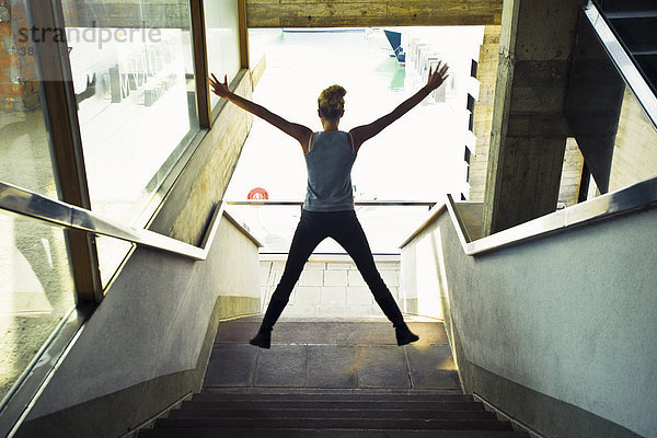 Teenagerin im Treppenhaus  Springen in der Luft  Rückansicht