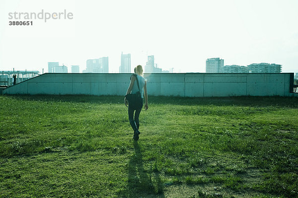 Teenagerin geht über Gras  städtische Skyline im Hintergrund