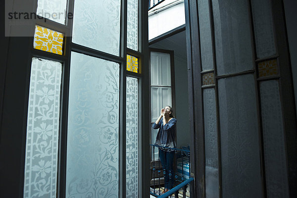 Teenagermädchen auf dem Balkon ruft in die nahegelegene Wohnung