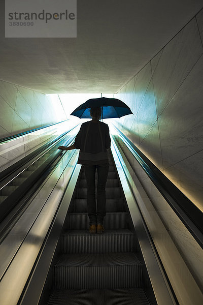 Aufsteigende Rolltreppe mit geöffnetem Regenschirm  vorbereitet für den Außeneinsatz