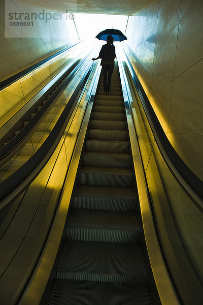 Aufsteigende Rolltreppe mit geöffnetem Regenschirm  vorbereitet für den Außeneinsatz