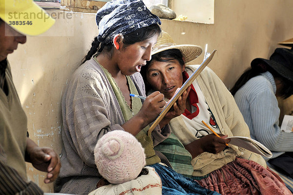Frauen in traditioneller Kleidung der Quechua tragen sich während eines Kurses in die Anwesenheitsliste ein  Bolivianisches Hochland Altiplano  Departamento Oruro  Bolivien  Südamerika