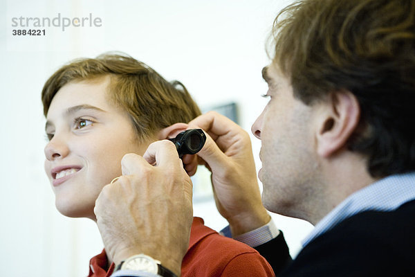 Arzt untersucht das Ohr eines jungen Patienten mit einem Otoskop