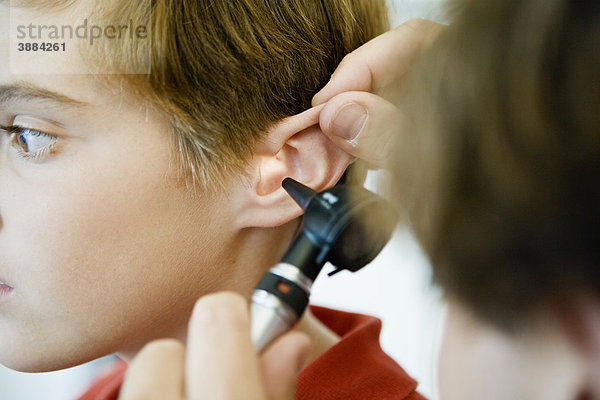 Untersuchung des Ohres eines jungen Patienten mit dem Otoskop