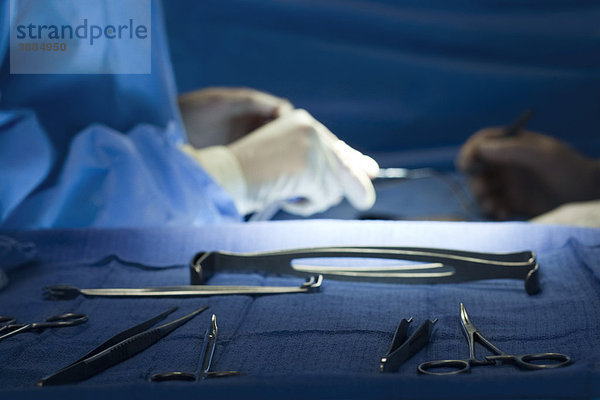Chirurgische Instrumente auf einem Tablett  Chirurgen im Hintergrund operieren