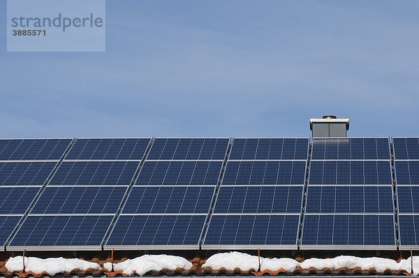 Solarmodule auf Hausdach mit Schneeresten  regenerative Energie