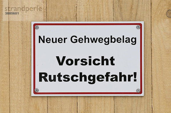 Sign on wooden board fence  Neuer Gehwegbelag Vorsicht Rutschgefahr  new walkway surface  caution slip hazard!