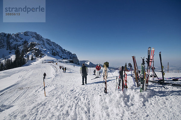 Blick von der Sonnenalm zur Bergstation der Kampenwandbahn  hinten die Scheibenwand  vorne Skier im Schnee  dahinter Spaziergänger auf dem Weg zur Seilbahn  Chiemgau  Bayern  Deutschland  Europa