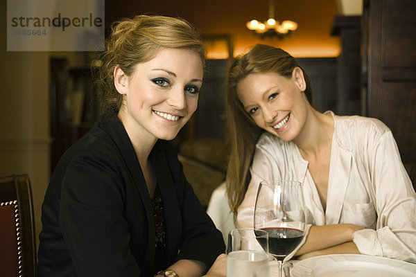 Frau bei einem Glas Wein mit Freundin im Restaurant