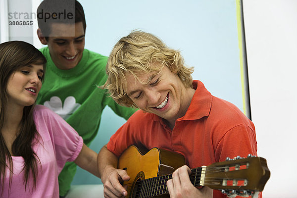 Junger Mann spielt Gitarre für seine Freunde