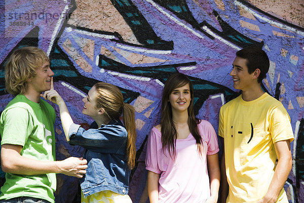 Junge Freunde  die vor der graffitierten Wand hängen