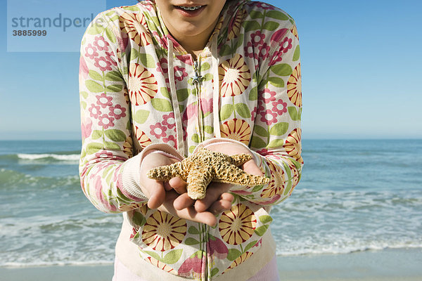 Teenagerin mit Seestern am Strand  geschnitten