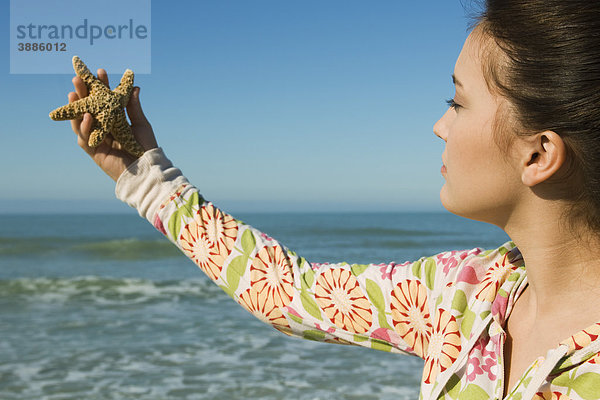 Teenagermädchen mit Seestern am Strand