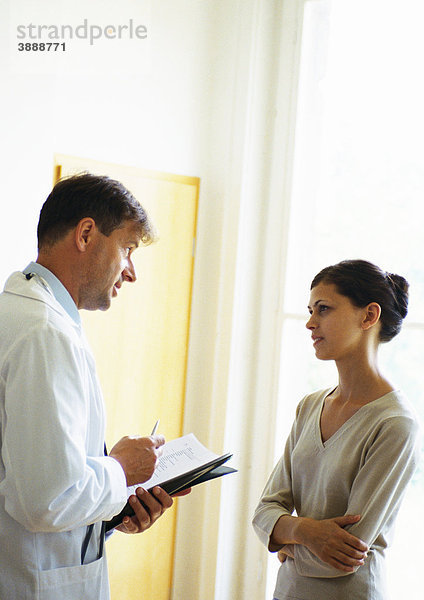 Arzt und Frau sprechen im Krankenhausflur