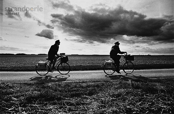 Zwei Personen auf Fahrrädern auf der Straße durch Felder  s/w