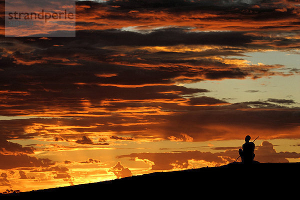 Australischer Aborigine sitzt auf einem Hügel und blickt in den Abendhimmel  Nordwest-Australien