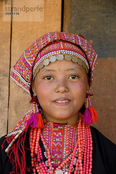 Portrait  Mädchen der Akha Pala Ethnie lächelt  Tracht  traditionelle Kleidung in Schwarz und Rosa  Kopftuch mit Silbermünzen  rote Perlenkette  Dorf Ban Latsang  Distrikt Muang Khoua  Provinz Phongsali  Laos  Südostasien  Asien