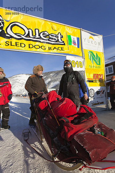 Hundeschlittenführer Normand Casavant steht an seinem beladenen Schlitten  im Gespräch mit der Rennleitung Hans Oettli nach der Ankunft in Dawson City  Yukon Quest 1000-Meilen Internationales Schlittenhunderennen 2010  Yukon Territory  Kanada