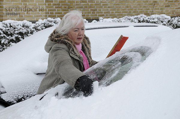 Frau befreit Autoscheibe von Schnee