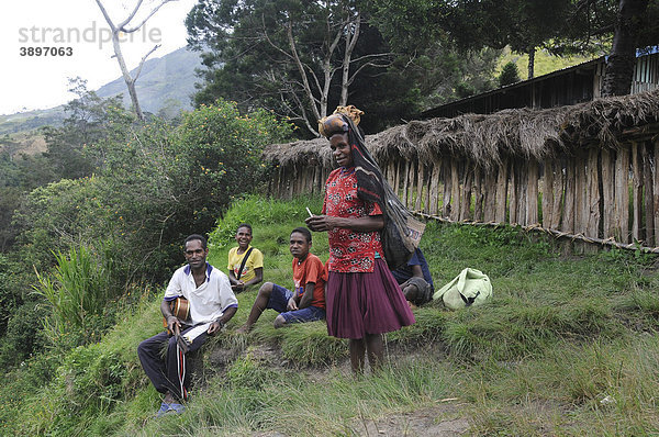 Danifrau kommt vom Feld und Jugendliche vom Volksstamm der Dani singen christliche Lieder mit Gitarrenbegleitung  Kurima  Baliem Tal  Irian Jaya  Indonesien  Südostasien  Asien