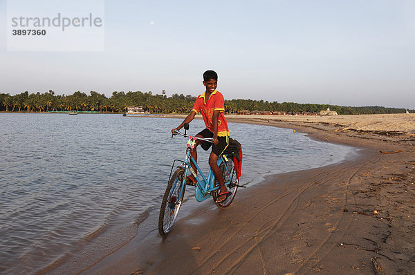 Stolzer Junge auf Fahrrad am Fluss Poovar  Backwater  Back Water  hinten Hotel Isola di Cocco Ressort  Puvar  Kerala  Südindien  Indien  Asien