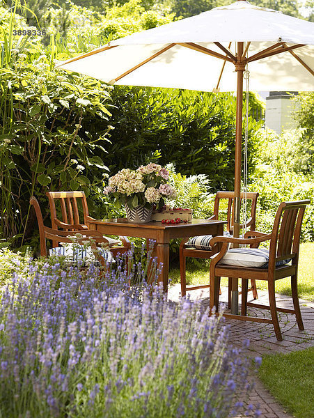 Romantischer Gartentisch mit Lavendel-Sträuchern in stimmungsvollem Sonnenlicht