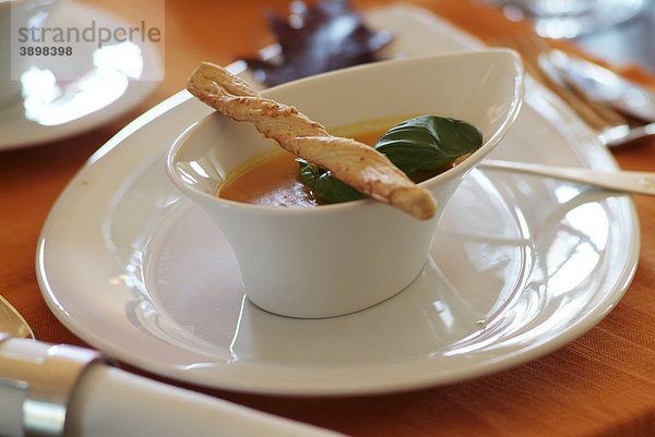 Kürbiscremesuppe in edlem  modernem weißem Geschirr auf gedecktem Tisch