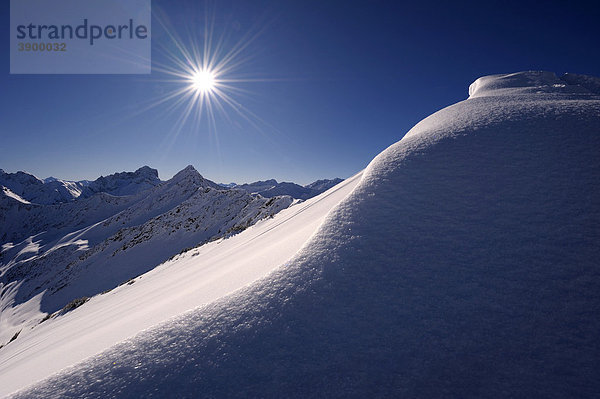 Schneewächte mit Sonnenstern vor Bergpanorama  Rietzlern  Kleinwalsertal  Vorarlberg  Österreich  Europa