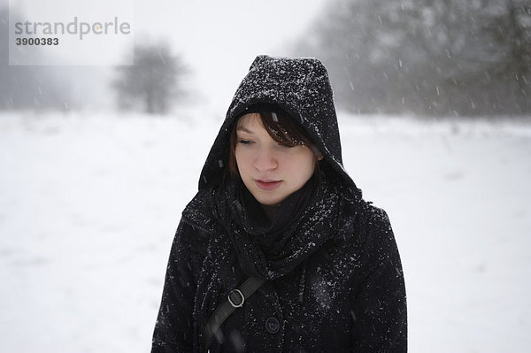 Junge Frau in einem Park im Schneetreiben