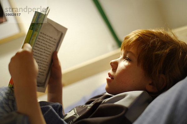 Kind  Junge beim Lesen im Bett