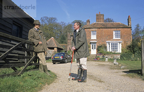 Farmer und Agrarwissenschaftler sprechen in der Zufahrt vor einem Bauernhaus miteinander  Hertfordshire  England  Vereinigtes Königreich  Europa