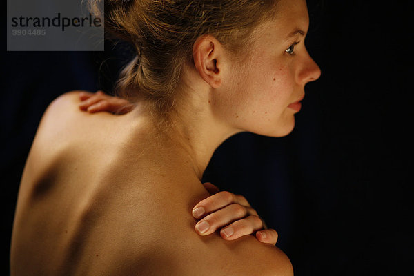 Junge Frau im Profil mit Händen auf den nackten Schultern