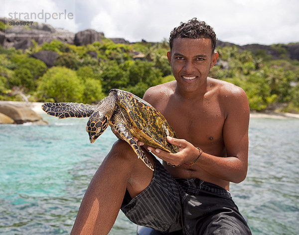 Kreolischer Guide zeigt eine Meeresschildkröte  Seychellen  Afrika  Indischer Ozean